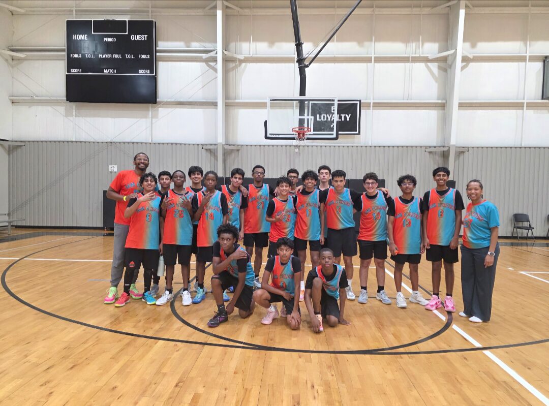 Hawk Athletics Academy team in teal and orange jerseys posing at center court with their coaches
